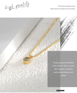 Macro detail of a gold minimalist necklace with a sparkling round zircon pendant