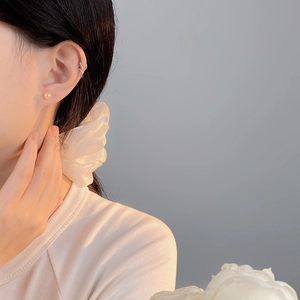 Elegant natural freshwater pearl stud earrings and ear cuff on model with soft lighting