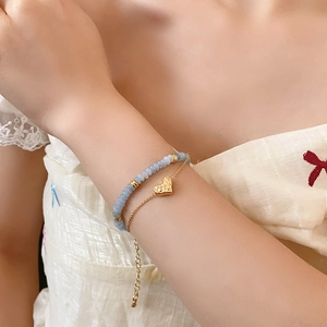Close-up of double-layer beaded bracelet with gold heart pendant on model wrist