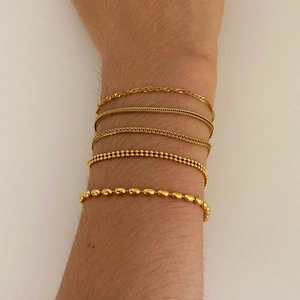 Minimalist gold plated stainless steel bracelet set with assorted link designs on model
