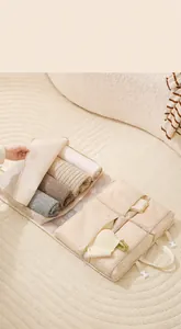 Dettaglio dell'organizzatore da viaggio beige con scomparti aperti per riporre i vestiti