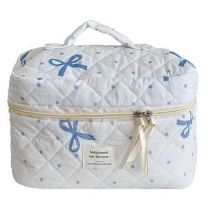 White cotton quilted makeup bag with blue polka dot bow pattern and sturdy top handle