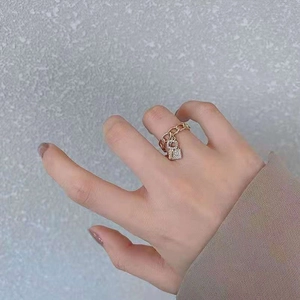 Détail macro d'une bague chaîne dorée avec breloques clé et cadenas serties sur une main