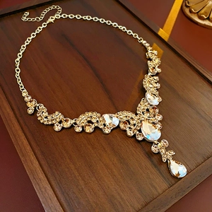Dettaglio di cristalli a goccia champagne su una collana dorata di lusso francese