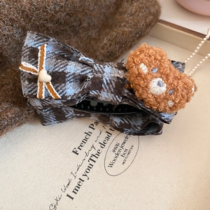 Detail of fabric plaid bow hair clip with plush bear and heart accent for hair styling