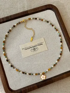 Close-up of tiger eye bead necklace with a white mother of pearl flower pendant