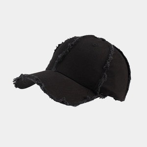 Close-up of distressed black cotton baseball cap showing frayed edges and vintage texture