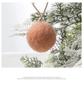 Macro detail of a peach wool felt ball ornament with jute rope on snowy pine branches