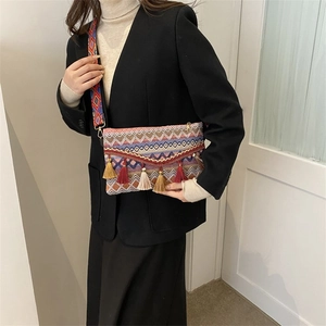 Close-up of bohemian woven crossbody bag with colorful tassels and geometric strap