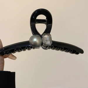 Detailed view of black geometric hair claw with grey faux pearl and crystal gemstone