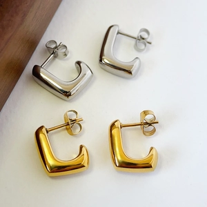 Detail of 14k gold and silver geometric C-shaped stud earrings in polished stainless steel
