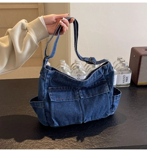 Macro detail of dark blue denim shoulder bag with utility pockets and adjustable strap
