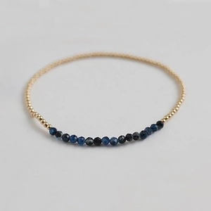 Macro detail of elastic beaded bracelet with faceted blue gemstones and gold beads