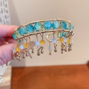 Détail du bracelet fait main en fil doré avec perles de cristal bleues et glands dorés