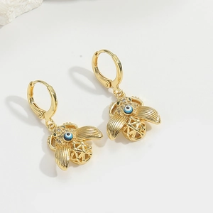 Close-up of gold-plated bee earrings featuring blue evil eye detail and fine crystals