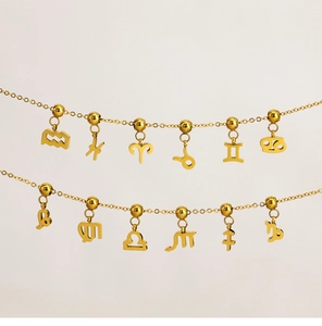 Macro detail of 18K gold-plated stainless steel zodiac pendants on fine chain jewelry