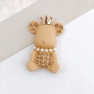 Macro detail of crown bear charm with beige matte finish and pearl rhinestone accents