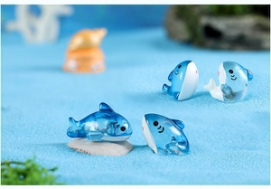 Detailed view of four cute blue resin shark figurines on a sandy seafloor background