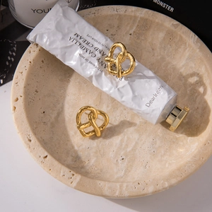 Détail de boucles d'oreilles nœuds en acier inoxydable plaqué or 18 carats sur plateau