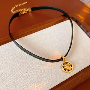 Detail of black choker necklace featuring a gold starburst pendant with clear zircon gem