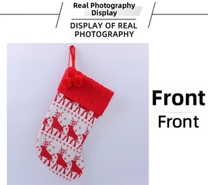 Detail of knitted Christmas stocking with red reindeer patterns and soft pom-poms