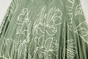 Close-up of green fabric with white leaf print showing smooth silk-like texture