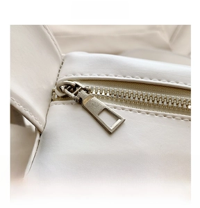 Close-up of smooth metal zipper and premium white leather texture on tote bag
