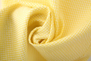 Macro shot of yellow and white gingham seersucker fabric with soft pleated texture