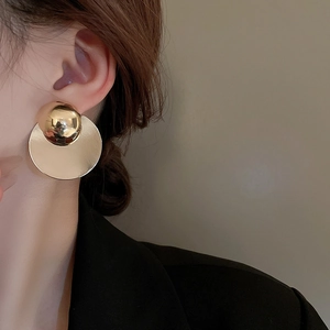 Macro side view of a model wearing minimalist golden geometric round disc drop earrings