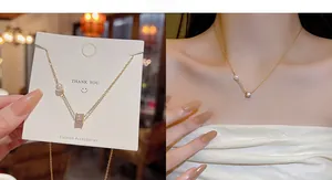 Detail of gold titanium necklace featuring a white pearl and zircon bow pendant on model