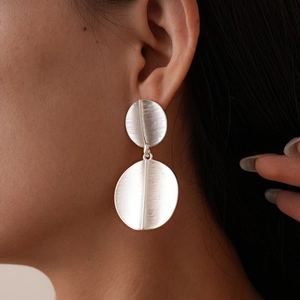 Macro detail of geometric matte silver earrings with textured brushed metal finish