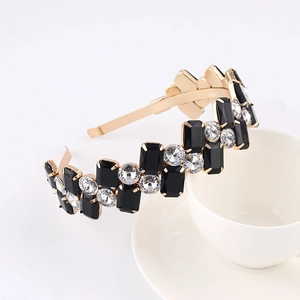 Macro shot of gold headband with black rectangular gems and clear round rhinestones