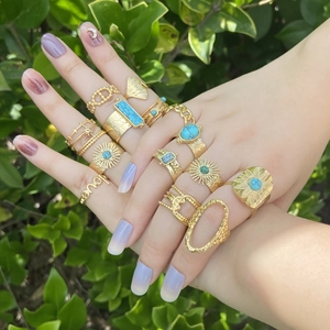 Set of gold stainless steel rings with turquoise stones and sunburst patterns on hands