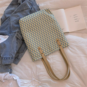 Détail du sac cabas en toile fleurie avec anses en cuir et rivets métalliques renforcés