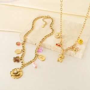 Detailed view of gold multi-pendant necklace with floral and bear charms on marble