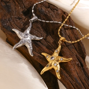 Gold and silver starfish necklaces with sparkling zircons on a rustic wood background