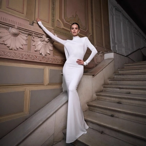 Elegante abito bianco lungo a maniche lunghe con schiena scoperta su una scala
