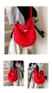 Detail of red plush tote bag with white label worn on shoulder in a lifestyle setting