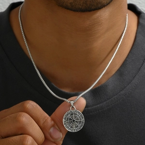 Silver compass pendant necklace with black gemstone on male model wearing a black t-shirt