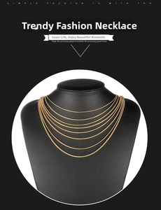 Close-up of a layered gold snake bone chain necklace displayed on a black mannequin