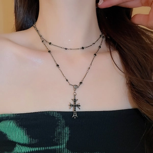 Close-up of double-layered gothic necklace with silver cross pendant and black gemstones