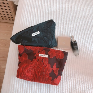 Detailed close-up of premium fabric cosmetic bags with 3D rose embroidery and brand label