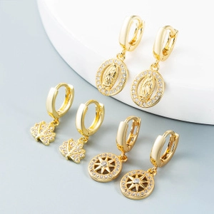 Detail of three pairs of gold earrings with turquoise, maple leaf, and sunburst pendants