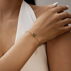 Close-up of elegant gold tulip bracelet with red and green crystals on female wrist