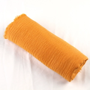 Close-up of orange cotton linen scarf showing woven texture and frayed edge details