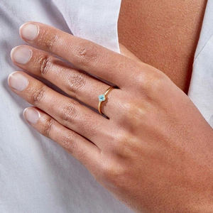 Detail of 18K gold dainty ring featuring a turquoise clover on model finger