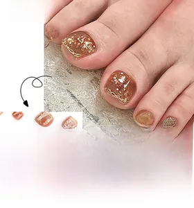 Detailed view of amber brown press-on toenails with glitter and gold wire design