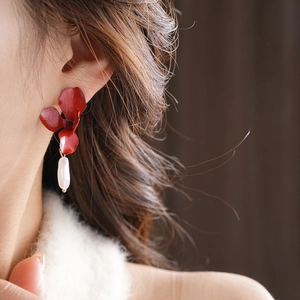 Detail of red floral enamel earring with baroque pearl pendant on a female model