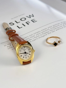 Close-up of small vintage women quartz watch with brown leather strap and gold ring
