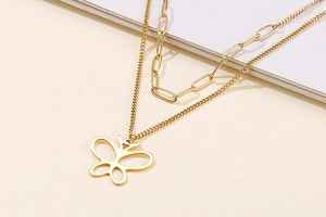Close-up of golden double-layer necklace featuring a minimalist butterfly pendant on a link chain